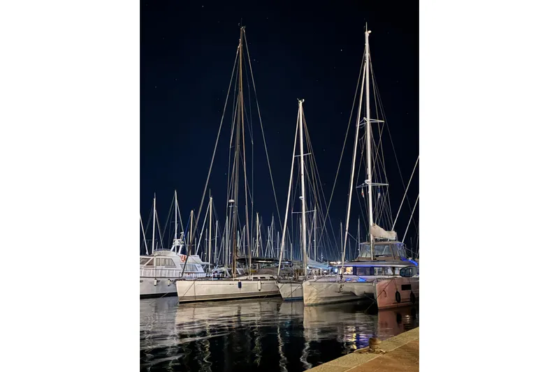  Yacht Photos Pics Night view of a 2022 Lagoon 46 catamaran docked among sailboats.