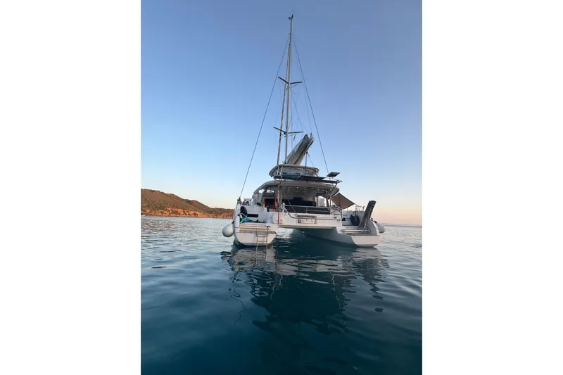  Yacht Photos Pics 2022 Lagoon 46 catamaran anchored in calm waters at sunset.