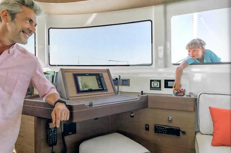  Yacht Photos Pics Man smiling inside 2022 Lagoon 46 yacht cockpit, child reaching through window.