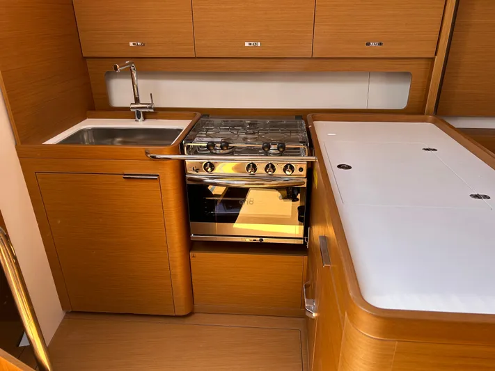  Yacht Photos Pics 2023 Beneteau First 44 yacht kitchen with modern wood cabinetry and stainless steel appliances.