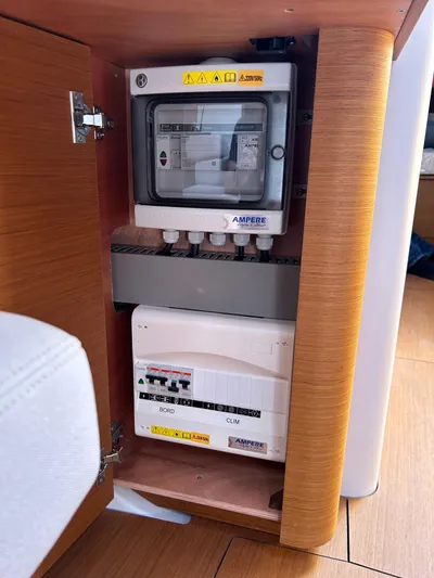  Yacht Photos Pics Electrical panel inside 2023 Beneteau First 44 yacht, featuring circuit breakers and wooden cabinetry.