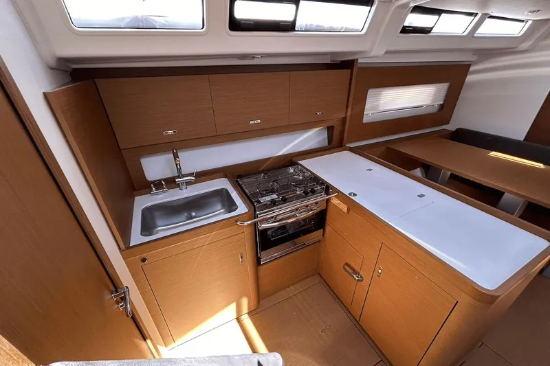  Yacht Photos Pics Modern kitchen interior of 2024 Beneteau First 44 yacht with wood cabinetry and stainless steel sink.