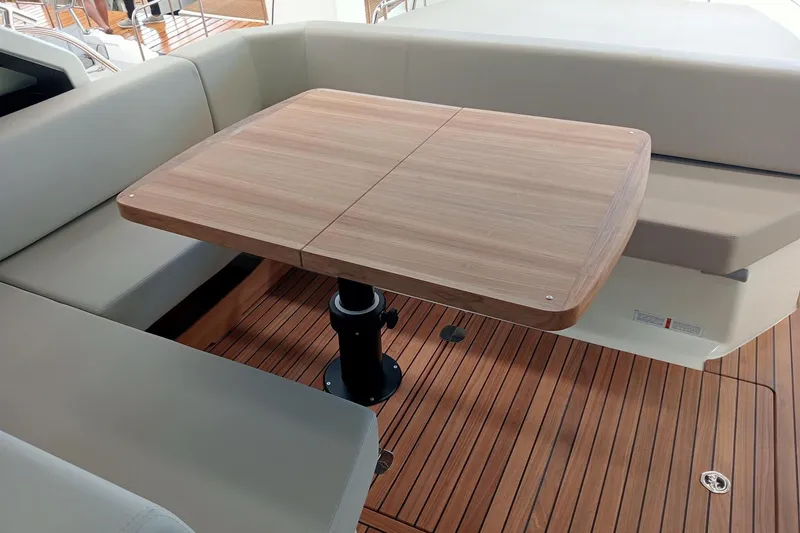  Yacht Photos Pics Luxury seating area on 2025 Cranchi M44HT yacht with wooden table and cushioned benches.