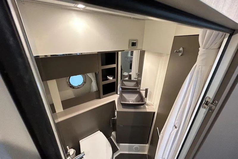  Yacht Photos Pics Modern bathroom interior of 2025 Cranchi M44HT yacht with sleek fixtures and porthole window.