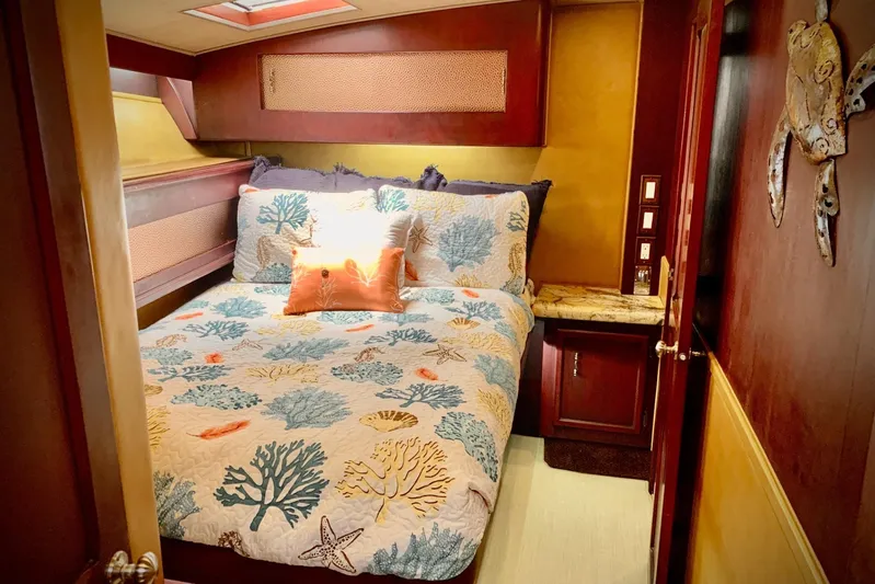 Dolce Vita Yacht Photos Pics Cozy bedroom in 1984 Egg Harbor 48' Flybridge with nautical-themed bedding and warm wood accents.