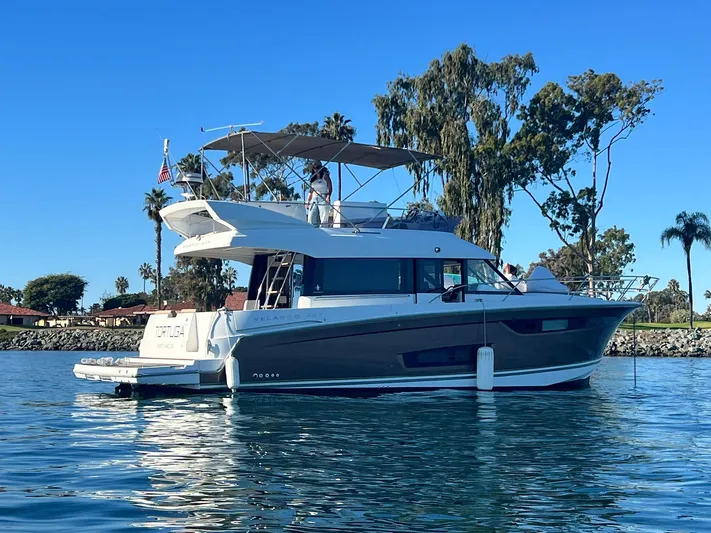 Tortuga Yacht Photos Pics 2017 Jeanneau Velasco 43F yacht on calm water, surrounded by trees and clear blue sky.