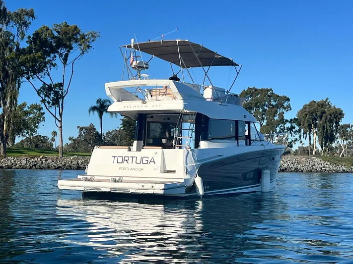 Tortuga Yacht Photos Pics 2017 Jeanneau Velasco 43F yacht on calm water, surrounded by trees.