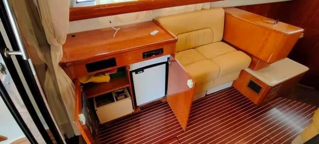  Yacht Photos Pics 2004 Cranchi Atlantique 40 interior with beige seating, wooden cabinetry, and mini fridge.