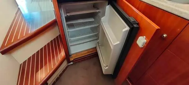  Yacht Photos Pics Interior of 2004 Cranchi Atlantique 40 yacht with open refrigerator and wooden stairs.