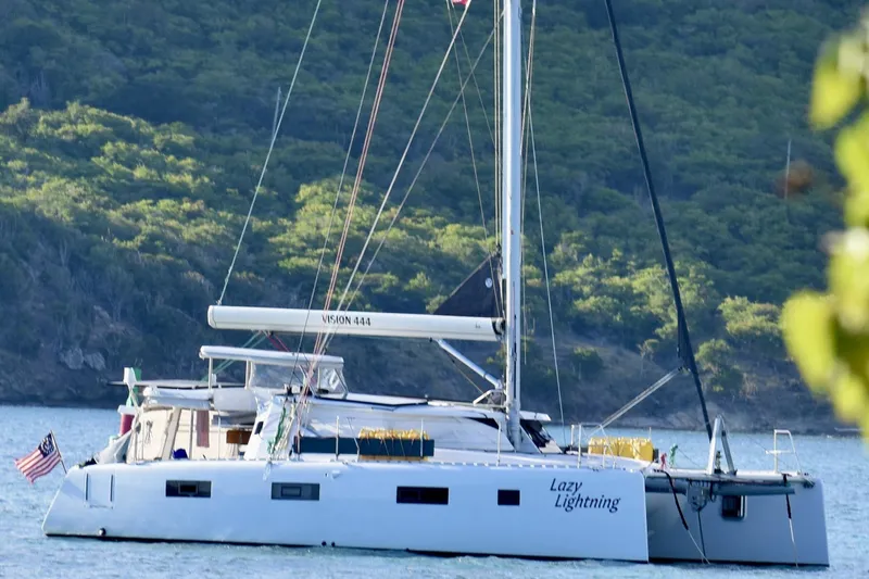 Lazy Lightning Yacht Photos Pics Sailing catamaran Vision 444, 2021 model, anchored in scenic bay with lush green hills.