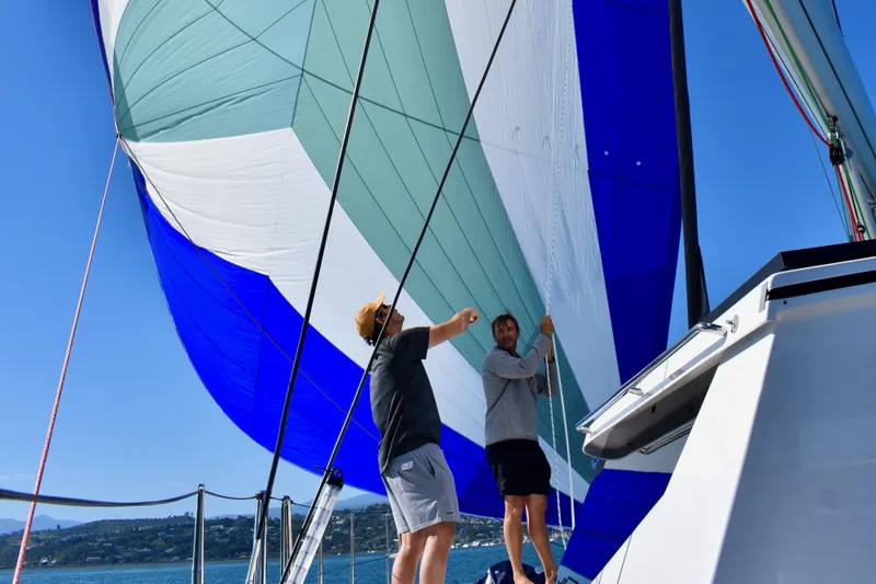 Lazy Lightning Yacht Photos Pics Two people adjusting a colorful sail on a Vision 444 yacht, 2021 model.