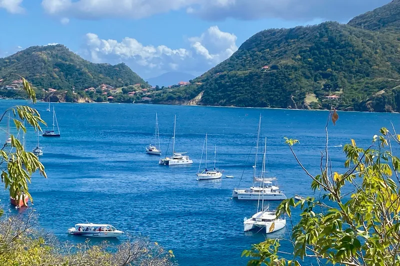 Lazy Lightning Yacht Photos Pics Sailboats anchored in a scenic bay surrounded by lush green hills.
