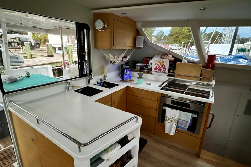 Lazy Lightning Yacht Photos Pics Modern yacht kitchen interior with wooden cabinets, stove, and large windows. Vision 444, 2021 model.
