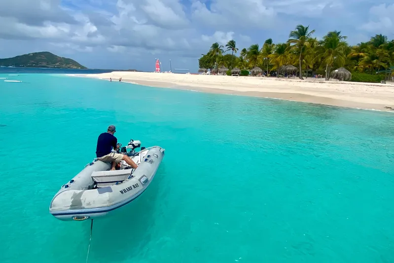 Lazy Lightning Yacht Photos Pics Man on inflatable boat approaching tropical beach with turquoise water, Vision 444, 2021.