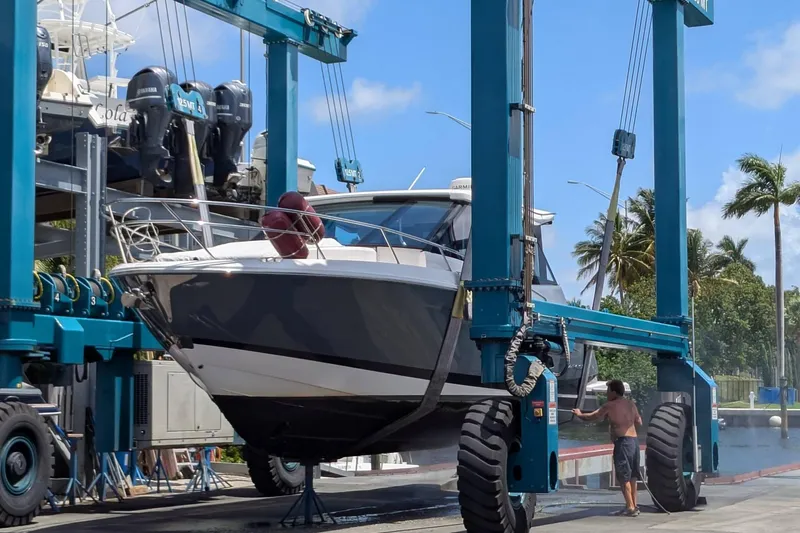  Yacht Photos Pics 2021 Regal 36 XO boat being lifted by a blue crane at a marina.