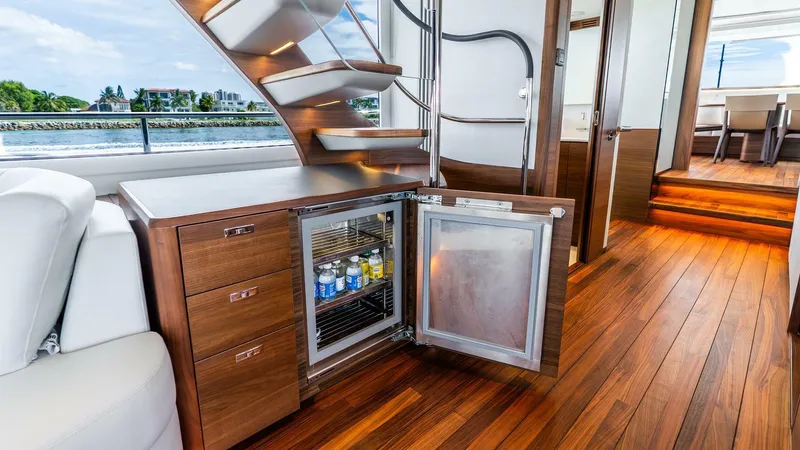 Cosa Bella Yacht Photos Pics Luxurious 2024 Princess X80 yacht interior with wooden flooring and open mini fridge.