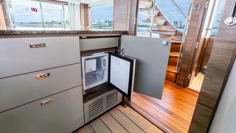 Cosa Bella Yacht Photos Pics Luxurious 2024 Princess X80 yacht interior with open mini fridge and elegant wood flooring.