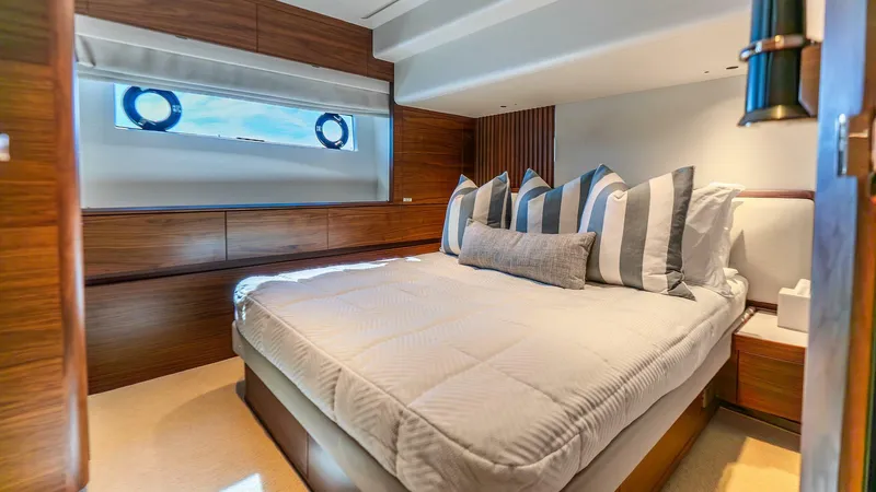 Cosa Bella Yacht Photos Pics Luxurious bedroom interior of 2024 Princess X80 yacht with striped pillows and wooden accents.