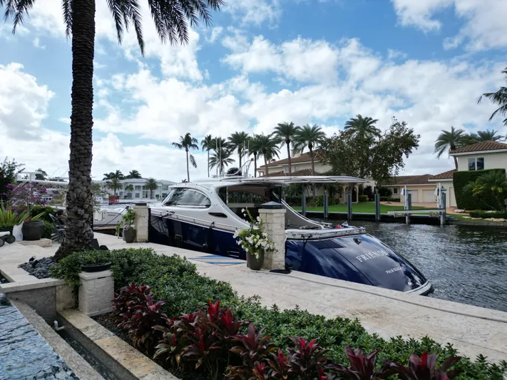 Friendship Yacht Photos Pics 2023 Zeelander 5 yacht docked by a luxurious waterfront property with palm trees.