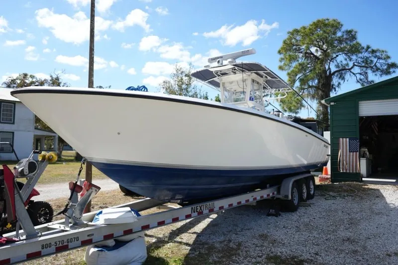  Yacht Photos Pics 2000 Contender 36 Open boat on trailer, parked outdoors near a green building.