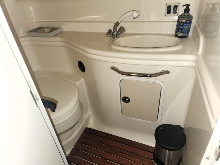 Keep The Faith Yacht Photos Pics 2005 Sea Ray 340 Sundancer bathroom with sink, toilet, and wooden floor mat.