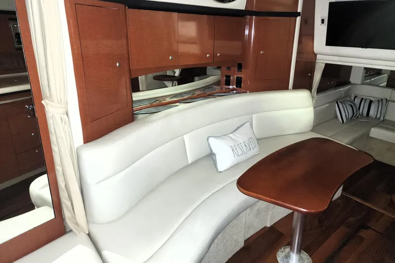 Keep The Faith Yacht Photos Pics Interior of 2005 Sea Ray 340 Sundancer with curved seating and wooden table.