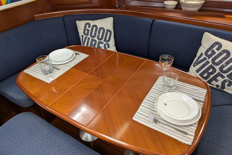 Laylay Yacht Photos Pics Dining area of 2003 Beneteau Oceanis Clipper 473 with "Good Vibes" pillows and table setting.