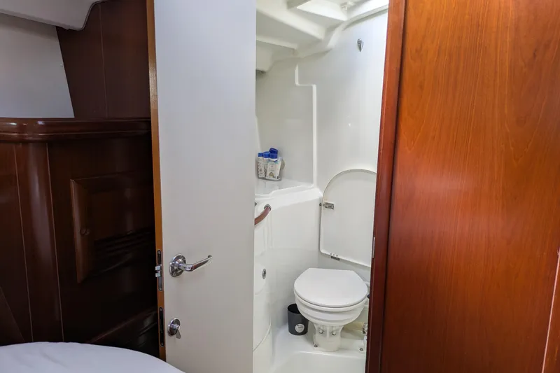 Laylay Yacht Photos Pics Beneteau Oceanis Clipper 473 yacht bathroom interior, featuring a compact toilet and wooden door.