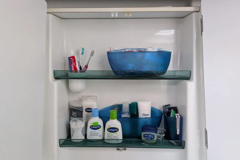 Laylay Yacht Photos Pics Bathroom cabinet with toiletries, including toothpaste, toothbrushes, and skincare products.
