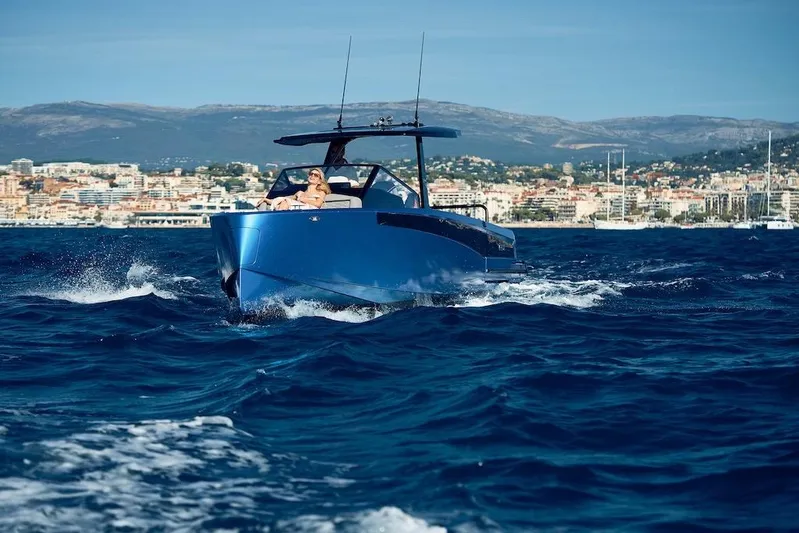  Yacht Photos Pics 2026 Virtue V10 T-Top boat cruising on blue ocean near coastal city.