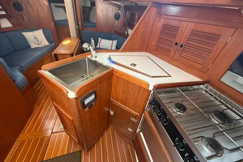  Yacht Photos Pics 1998 Tartan 3500 yacht interior with wooden cabinetry, sink, stove, and cozy seating area.
