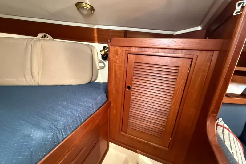  Yacht Photos Pics Cozy cabin interior of 1998 Tartan 3500 sailboat with wooden cabinetry and blue bedding.