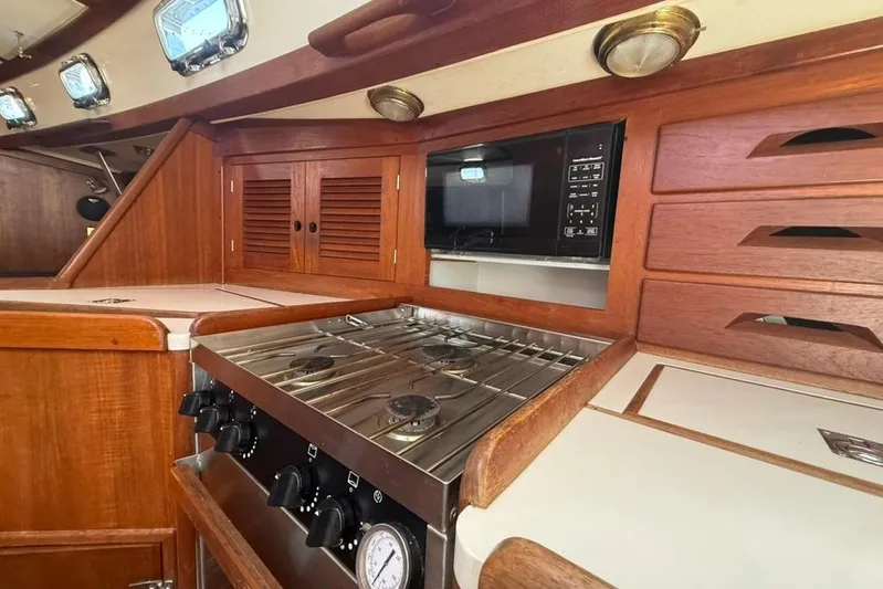  Yacht Photos Pics 1998 Tartan 3500 yacht kitchen with stove, microwave, and wooden cabinetry.