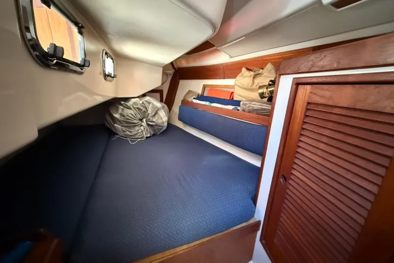  Yacht Photos Pics Interior cabin of a 1998 Tartan 3500 sailboat with blue bedding and wooden accents.