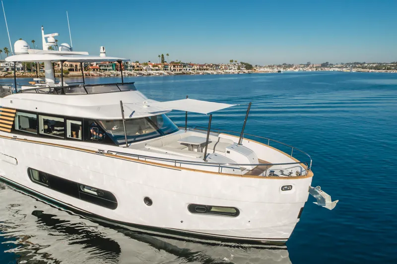 66 Magellano Yacht Photos Pics 2023 Azimut Magellano 66 yacht cruising on calm waters near a coastal town.