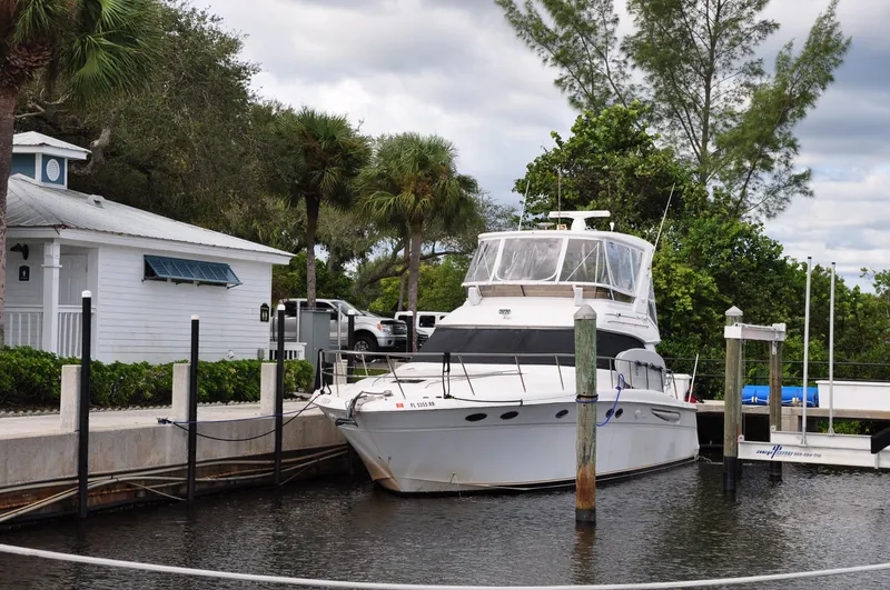  Yacht Photos Pics 1998 Sea Ray 480 Sedan Bridge docked at a marina with lush greenery.