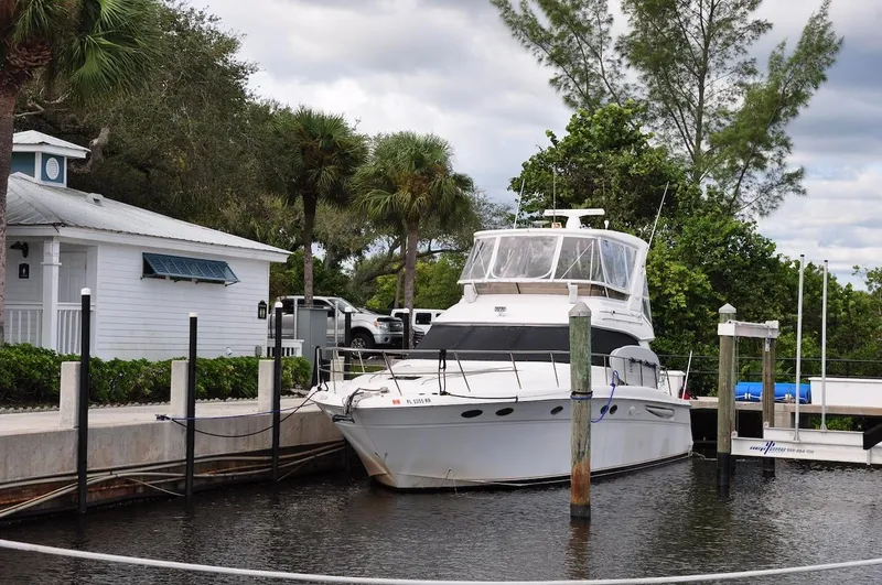  Yacht Photos Pics 1998 Sea Ray 480 Sedan Bridge docked at a marina with lush greenery.