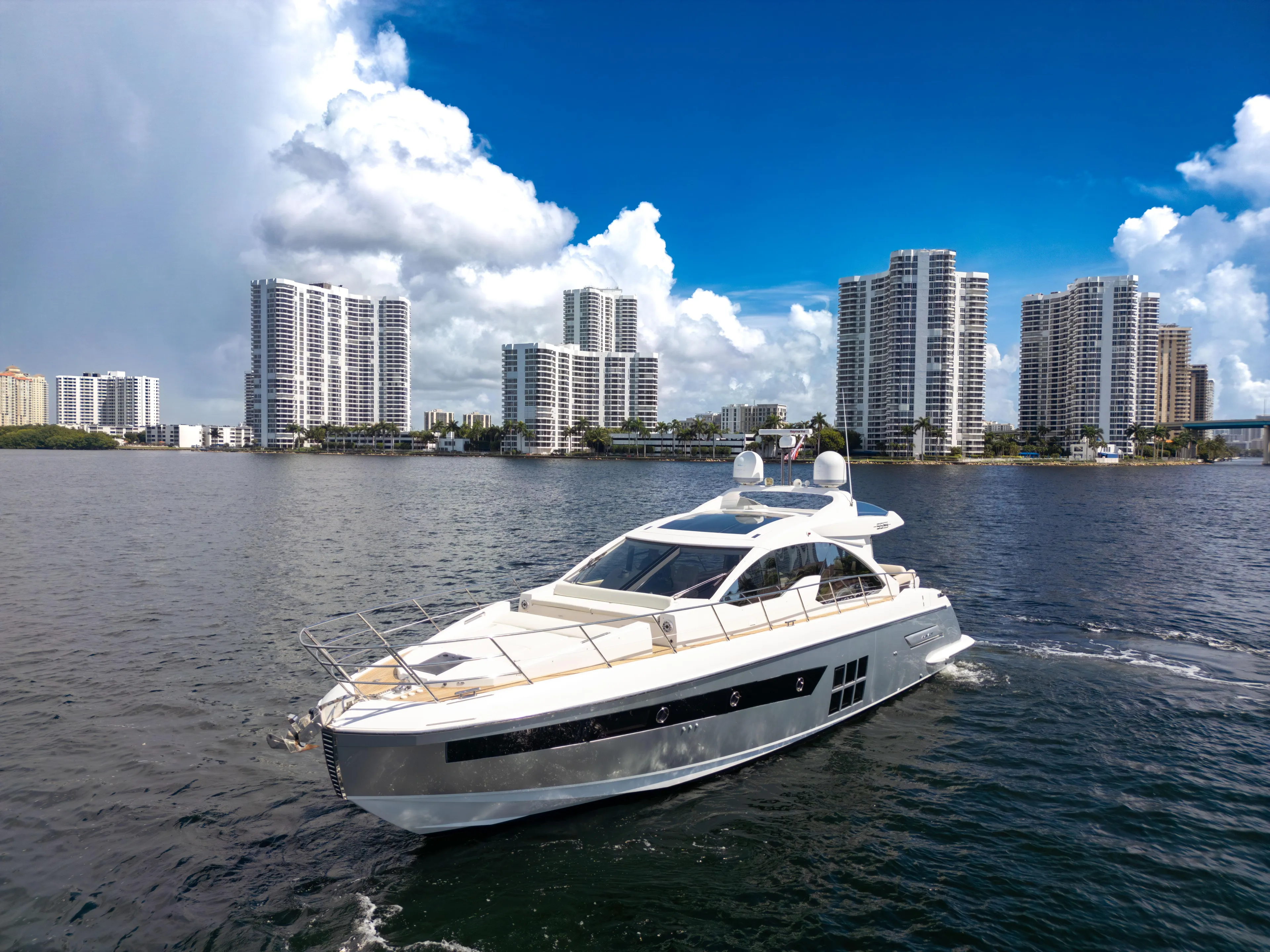 Ey IV Yacht Photos Pics 2016 Azimut 55S yacht cruising near city skyline under blue sky.