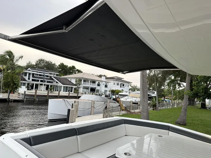  Yacht Photos Pics Galeon 650 Sky 2019 yacht with shaded seating area, docked near waterfront homes.