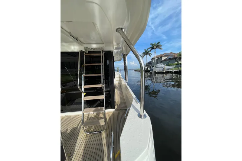  Yacht Photos Pics 2025 Beneteau Swift Trawler 41 Fly deck with ladder, overlooking waterfront homes and palm trees.