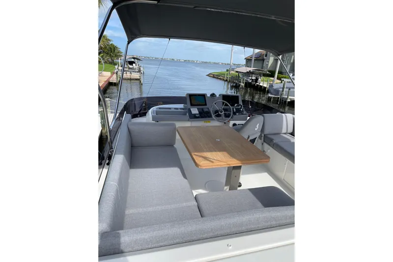  Yacht Photos Pics 2025 Beneteau Swift Trawler 41 Flybridge with seating and table, overlooking a serene waterfront.
