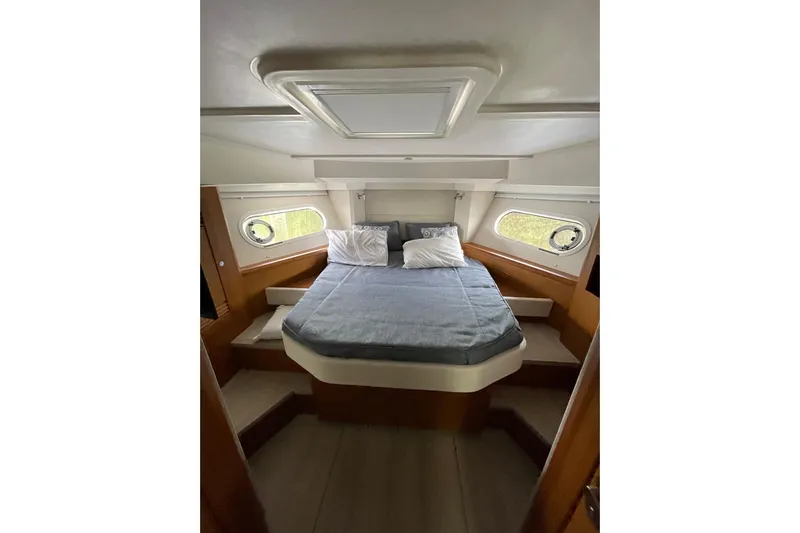  Yacht Photos Pics 2025 Beneteau Swift Trawler 41 Fly cabin with bed, portholes, and wooden interior.