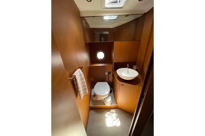  Yacht Photos Pics 2025 Beneteau Swift Trawler 41 Fly bathroom with wood finish, sink, and porthole window.
