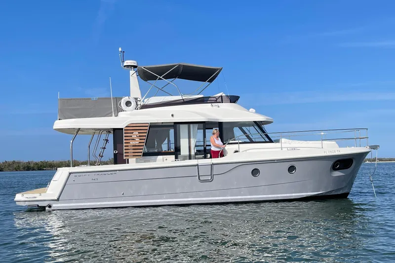  Yacht Photos Pics 2025 Beneteau Swift Trawler 41 Fly on calm water under clear blue sky.