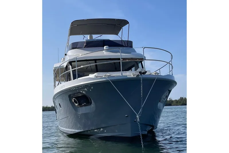  Yacht Photos Pics 2025 Beneteau Swift Trawler 41 Fly anchored on calm water under clear blue sky.