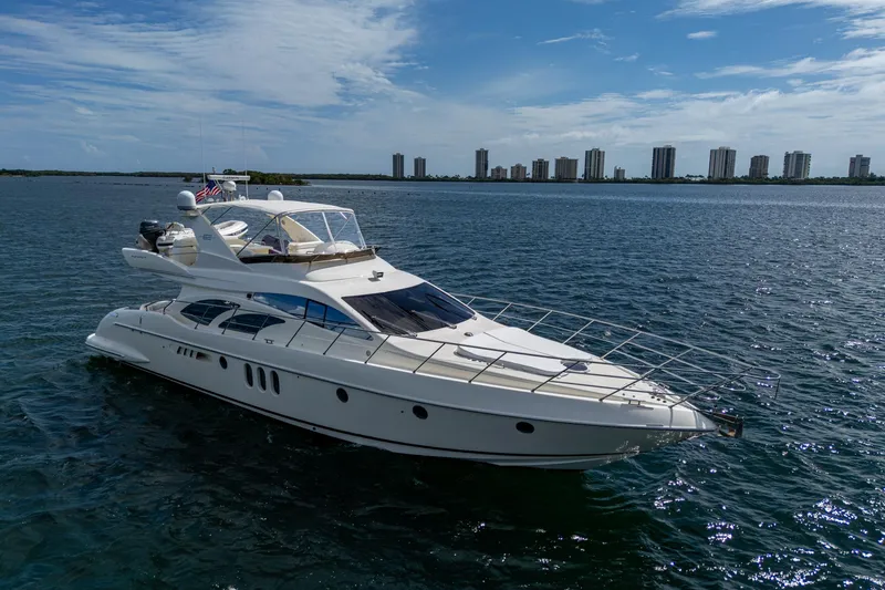 To Life! Yacht Photos Pics Luxurious 2005 Azimut Fly 62 yacht cruising on open water with city skyline backdrop.