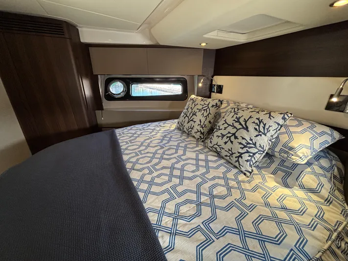 Skye Yacht Photos Pics Luxurious bedroom interior of 2019 Azimut Fly 50 yacht with patterned bedding and porthole window.