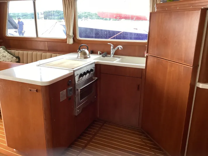 Sea Mist Yacht Photos Pics 1991 MDI Sedan Flybridge kitchen with stove, sink, and wooden cabinetry.