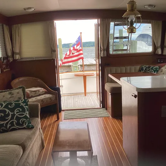 Sea Mist Yacht Photos Pics Interior of 1991 MDI Sedan Flybridge with American flag, cozy seating, and wooden flooring.