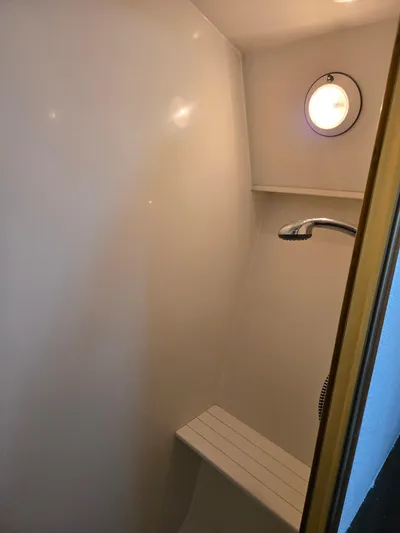 Bad To The Bone Yacht Photos Pics Shower area inside 1995 Egg Harbor Golden Egg 42 yacht, featuring a bench and porthole.